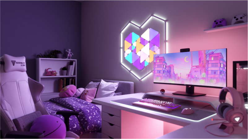 Ini adalah gambar Nanoleaf Shapes Triangles dan Triangles Mini di dinding atas meja dan di belakang monitor di tempat bermain gim. Lampu RGB ini memiliki lebih dari 16 juta warna dan sangat cocok untuk para pemain gim di rumah Anda. Light Panels pintar modular dihubungkan bersama dengan penghubung untuk membuat desain.