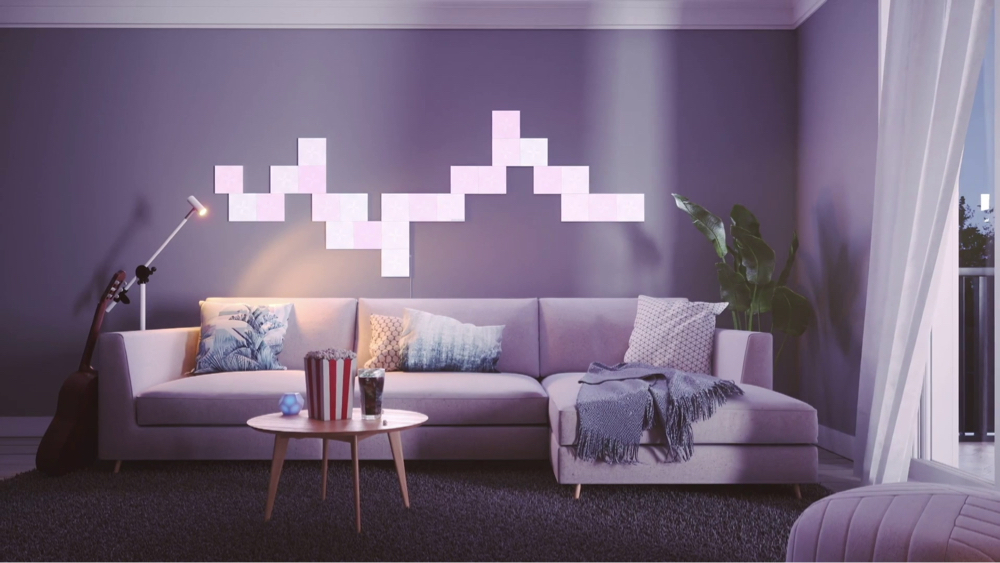 This is an image of a chill modern living room with Nanoleaf Canvas light squares behind the couch. The color changing RGB panels come in over 16 million bright and vibrant colors and are fully customizable with it's modular layout. The perfect living room lights for setting the vibe.