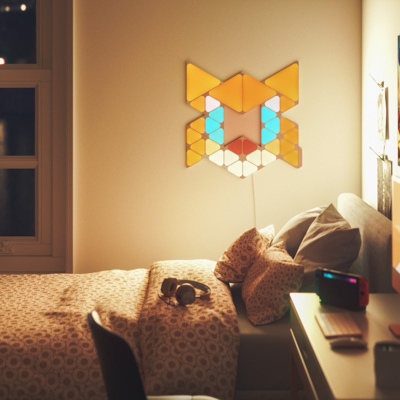 Nanoleaf Shapes Thread enabled color changing triangle and mini triangle smart modular light panels mounted to a wall in a bedroom as Tails. Sonic the Hedgehog 2. Tương tự với Philips Hue, Lifx. HomeKit, Trợ lý Google, Amazon Alexa, IFTTT.