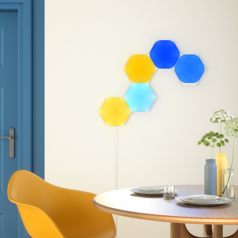 Light panels modular pintar heksagon yang dapat berubah warna dengan Thread Nanoleaf Shapes yang dipasang pada dinding di ruang makan. Mirip dengan Philips Hue, Lifx. HomeKit, Google Assistant, Amazon Alexa, IFTTT. 