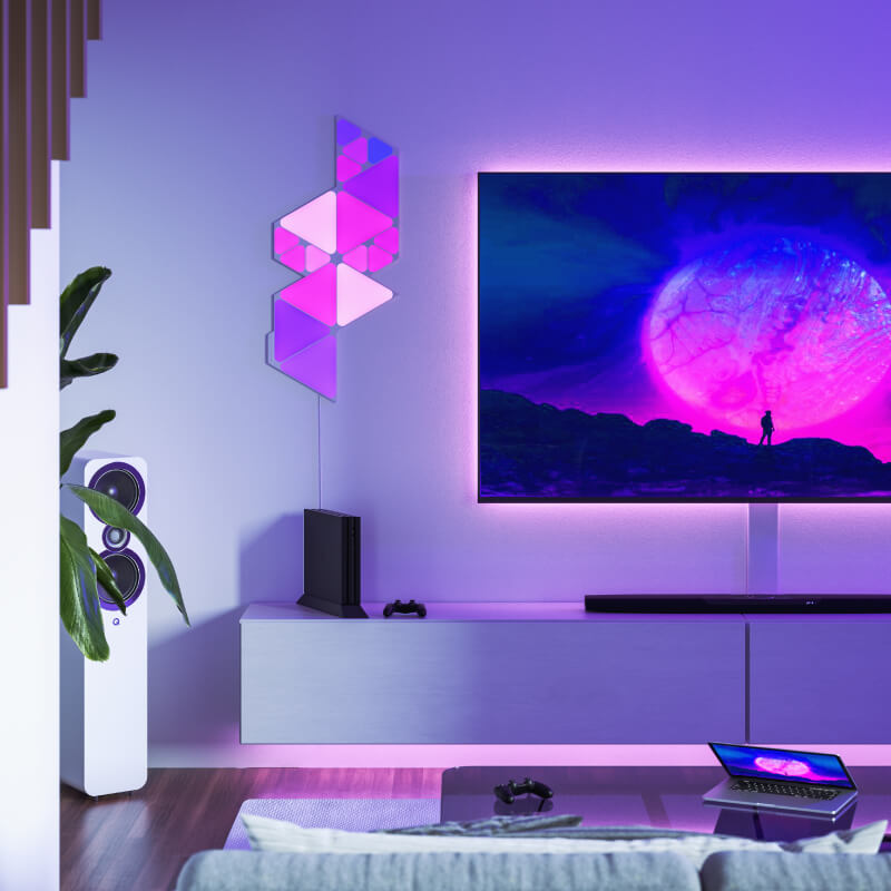Nanoleaf Shapes Thread enabled color changing mini triangle smart modular light panels mounted to a wall in a living room. Similar to Philips Hue, Lifx. HomeKit, Google Assistant, Amazon Alexa, IFTTT.